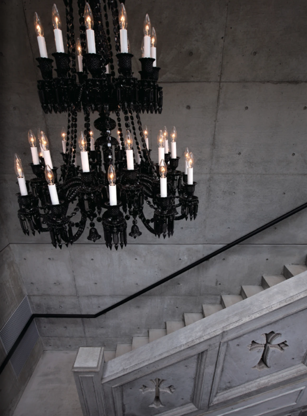 Dark chandelier above concrete staircase